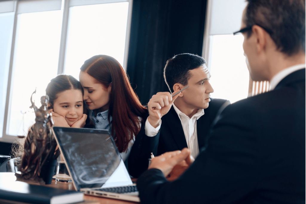 Two men in suits, one facing a laptop with a woman holding the face of a little girl